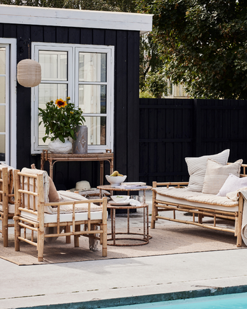 Koselig innredet balkong med lyslenker, myke puter og grønne planter – perfekt for avslappende sommerkvelder