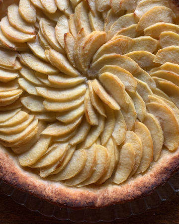 Hjemmebakt eplekake med eplebåter og kanel, servert på kakefat med en kule vaniljeis.
